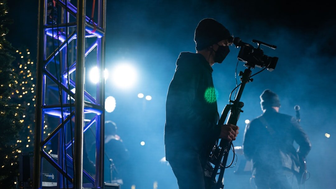 Broadcast camera filming a live event with bokeh lights